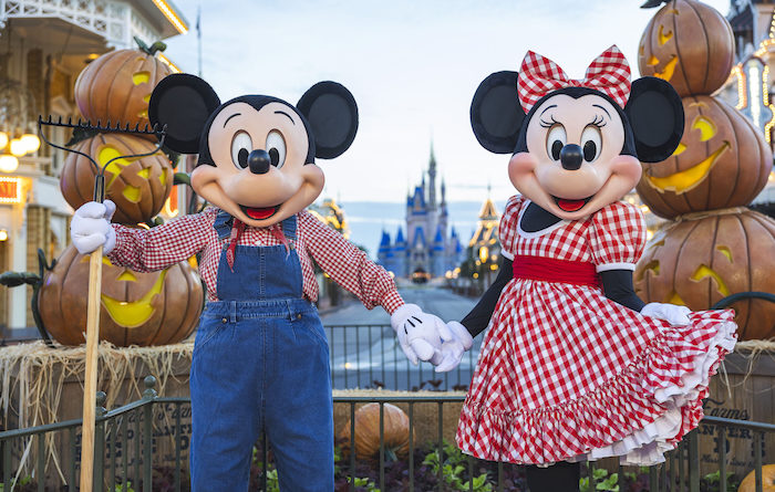 Mickey and Minnie pose in front of Halloween pumpkins at the Magic Kingdom